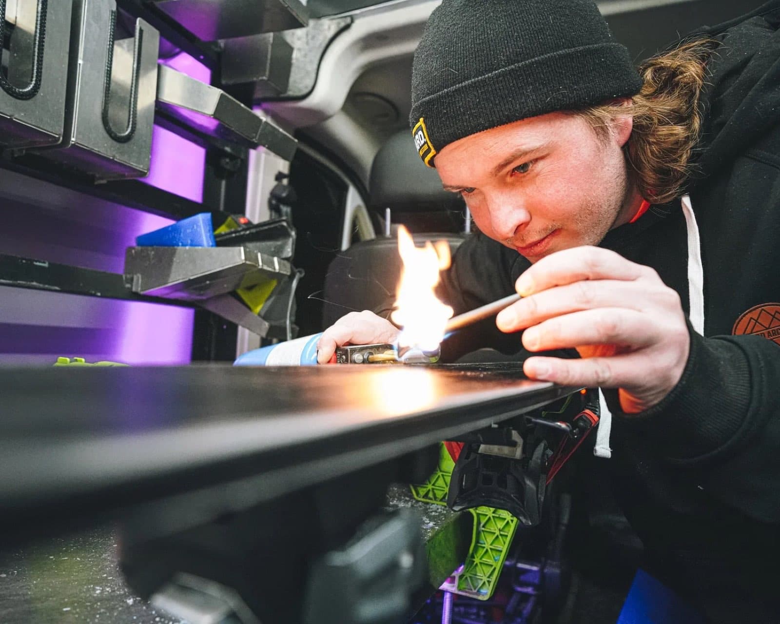 Tuning tech doing base repair on a ski inside the mobile tuning van