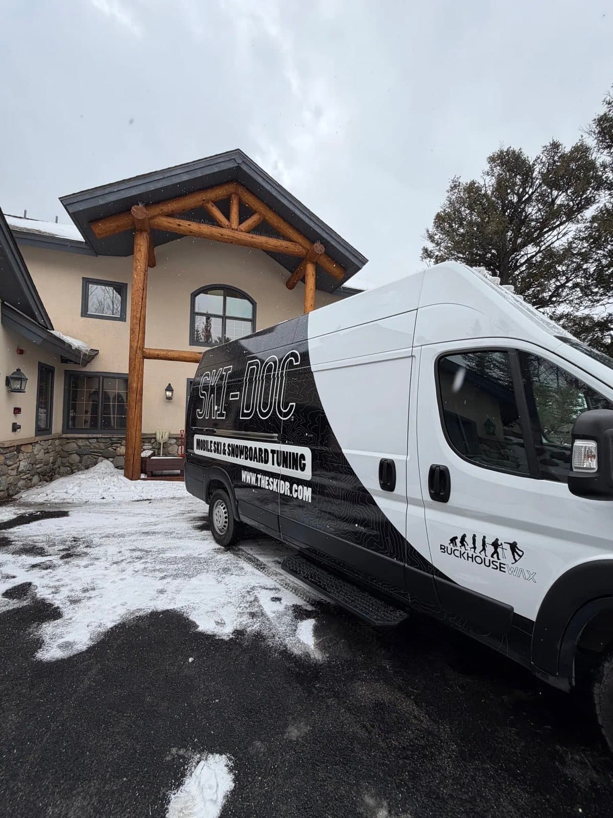 Mobile ski and snowboard tuning van parked at a snowy mountain lodge